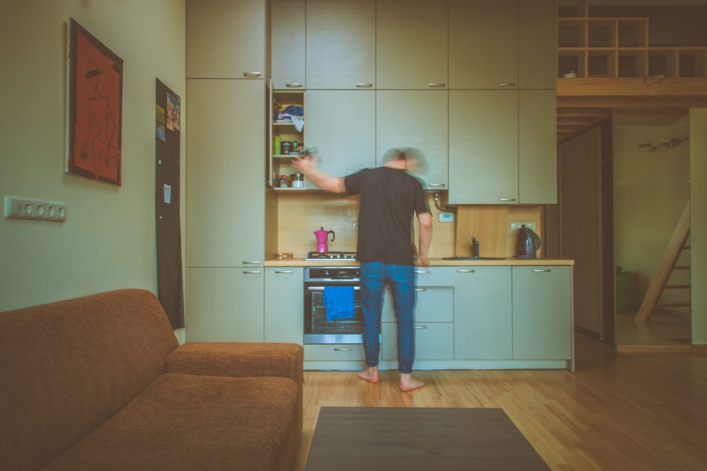 First time renter in the kitchen putting away items in the cupboard