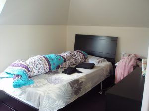 Property listing photo of a bedroom that shows a rolled blanket looking like a sleeping tenant